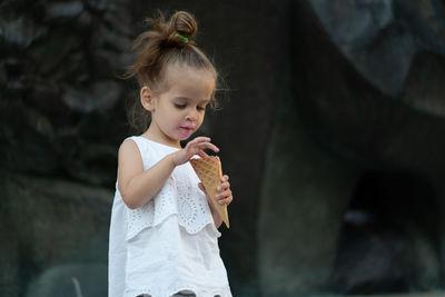 Cute girl eating ice cream against rock formation