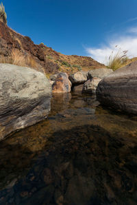 Rock formations on shore against sky