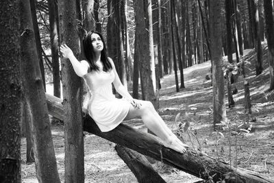 Young woman siting on log in forest