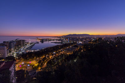 High angle view of illuminated city against clear sky at sunset