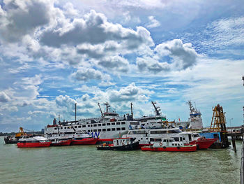 Fishing boats moored at harbor against sky