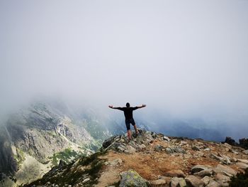 Full length of man standing on rock against sky