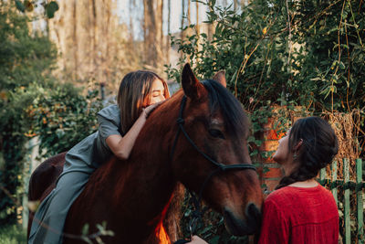 Woman sitting on horse while standing with friend