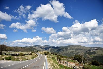 Country road along landscape against sky