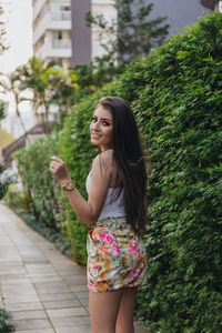 Young woman smiling while standing against trees