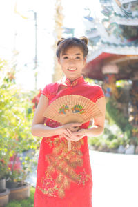 Portrait of smiling young woman standing against tree