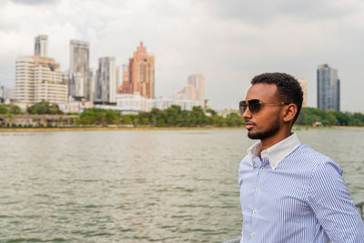 Portrait of young man standing against river