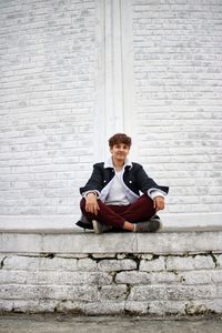 Portrait of young man sitting on wall