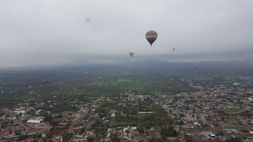 Hot air balloon flying over city against sky
