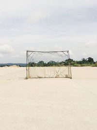 Soccer goal at beach against sky