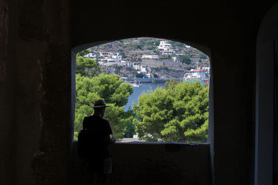 Man looking through window while standing in darkroom