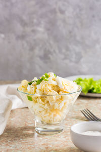 Homemade potato salad with egg and green onions in a bowl on the table. vertical view