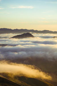 Scenic view of clouds over mountains during sunset