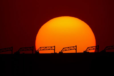 Silhouette information sign against orange sky