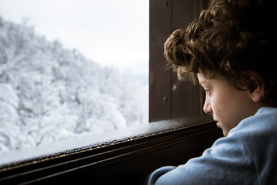 Close-up of boy looking through window