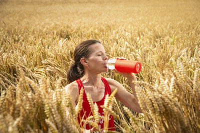 Woman drinking water from a bottle in a heatwave, countryside.