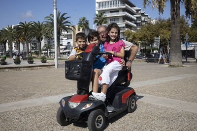 Portrait of senior man with grandchildren sitting on vehicle