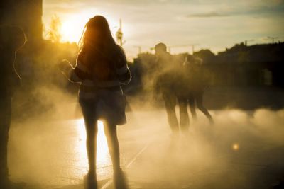 Rear view of silhouette woman against sky during sunset