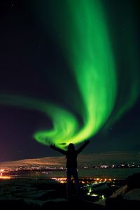 Rear view of silhouette man standing against sky at night