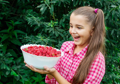 Smiling girl holding raspberries