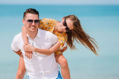 Portrait of father piggybacking daughter on beach