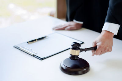 Midsection of lawyer holding gavel in courtroom