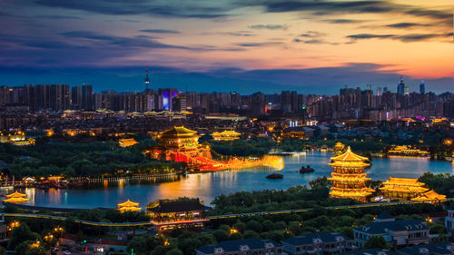 Illuminated buildings in city during sunset