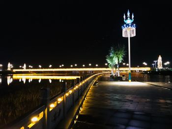 Illuminated bridge over city against sky at night