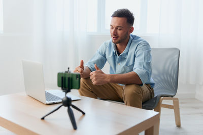 Portrait of young man using mobile phone while sitting at home