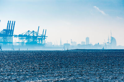 Cranes at commercial dock against sky