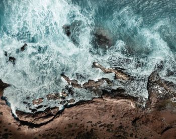 Aerial view of wave splashing on rocky coastline