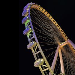 Low angle view of illuminated ferris wheel against sky at night