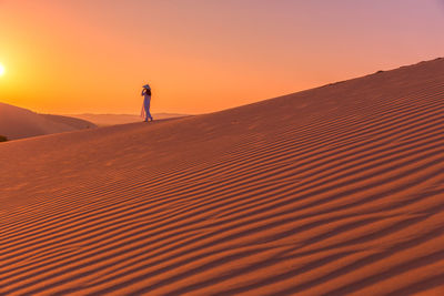 Silhouette of man standing on sand dune