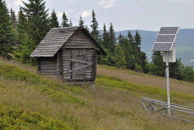 House against trees on landscape against sky