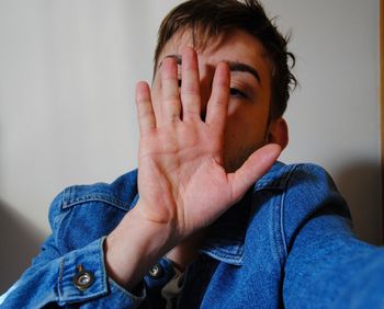 Portrait young man covering face with hand