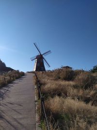 Traditional windmill on field against clear blue sky