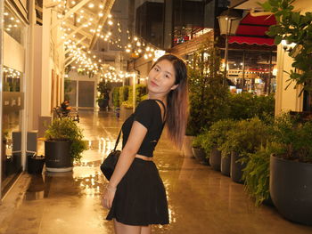 Portrait of young woman standing against building