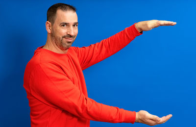 Young man with arms crossed against blue background