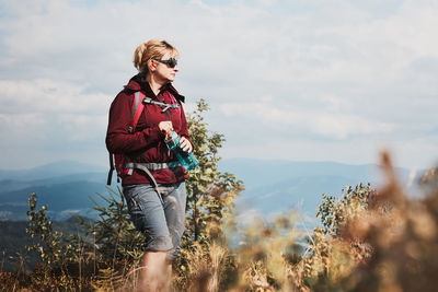 Woman with backpack hiking in mountains, spending summer vacation close to nature