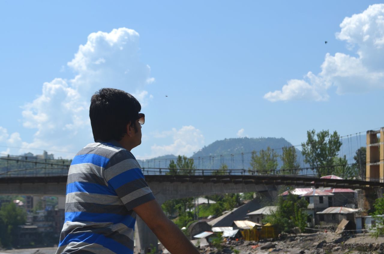 BOY STANDING AGAINST SKY