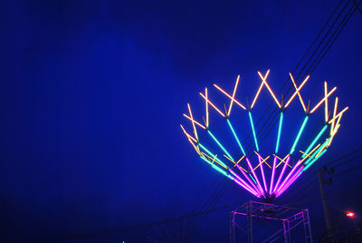 Low angle view of illuminated ferris wheel against blue sky