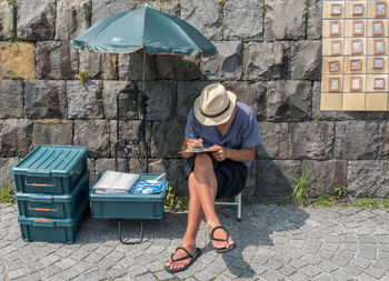 Rear view of woman sitting on sidewalk