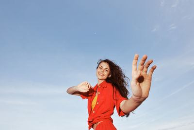 Portrait of young woman standing against sky