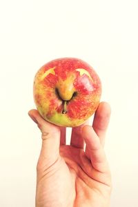 Close-up of hand holding fruit over white background