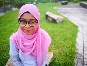 Portrait of smiling teenage girl sitting in park