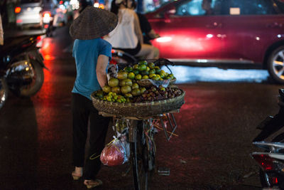 Rear view of woman transporting fruit on bicycle