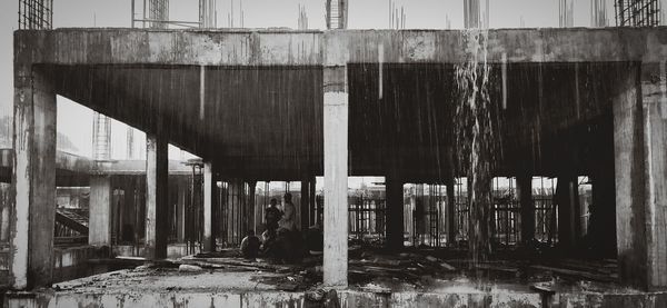 Men at incomplete building during rain