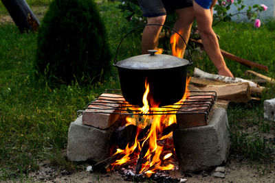 Man cooking fish soup in the iron bowler over a campfire. fish soup boils in cauldron at the stake