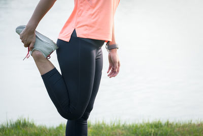 Midsection of woman standing on field against sky