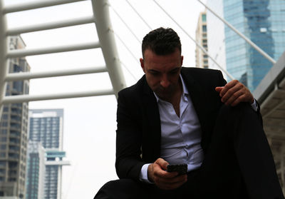 Tensed businessman using mobile phone in city